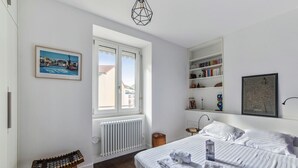 A bedroom with a bed, a radiator, a window, a bookshelf, and a framed picture on the wall. - Appartement Tromba - Welkeys (Lyon)