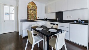 A modern kitchen with white cabinets, a black countertop, and a stained glass window above the sink. - Appartement Tromba - Welkeys (Lyon)