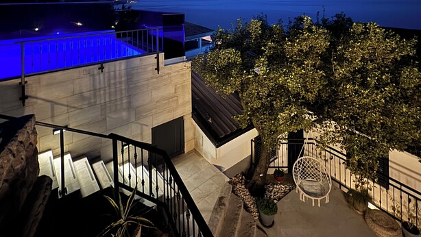 Uma área externa moderna com piscina, escadaria e espaço de estar com vista para um corpo d'água.
