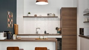Eine moderne Küche mit Kochinsel, zwei Holzkohlen und einer Pendelleuchte, sowie einer Mikrowelle auf der Arbeitsfläche.