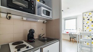 Une petite cuisine équipée d’une cuisinière, d’un four à micro-ondes et d’une machine à café.