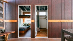A wooden interior with a bunk bed, a bench, and a table. - Volcano Escape  Epic Tiny Home on Lava Field with Volcano Views (Pāhoa)