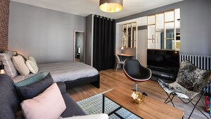 Ein modernes Hotelzimmer mit einem Bett, einer Couch, einem Couchtisch, einem Fernseher und einem Schreibtisch mit Stuhl.