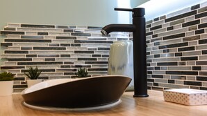 Eine moderne Küche mit einem schwarzen Wasserhahn, einer weißen Schüssel und einer gemusterten Seifenschale.