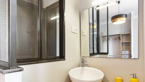 A bathroom with a white sink, wooden countertop, mirror, and a yellow soap dispenser. - Appartement Bourbon - Welkeys (Bayonne)
