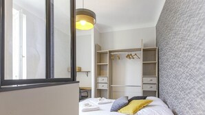 A bedroom with a bed, a wardrobe, and a desk. - Appartement Bourbon - Welkeys (Bayonne)