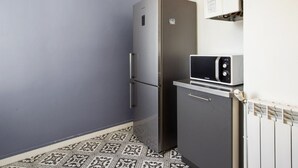 A compact kitchen with a refrigerator, microwave, and a small cabinet. - Appartement Bourbon - Welkeys (Bayonne)
