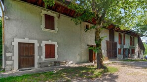A rustic building with a stone facade, wooden shutters, and a gravel driveway. - Studio Serena - Welkeys (Seynod)