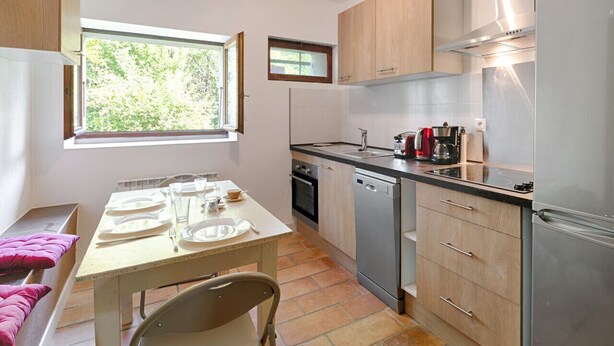 A compact kitchen with a dining area, a window, and a built-in oven. - Studio Serena - Welkeys (Seynod)