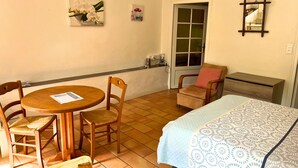 A room with a bed, a chair, a table, and a door. - Studio Serena - Welkeys (Seynod)