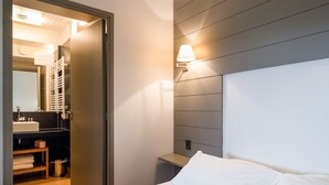 A hotel room with a bed, a nightstand, a wall-mounted lamp, and a bathroom visible through an open door. - Vieille Bourse - Studio close to stations and old city - Welkeys (Lille)