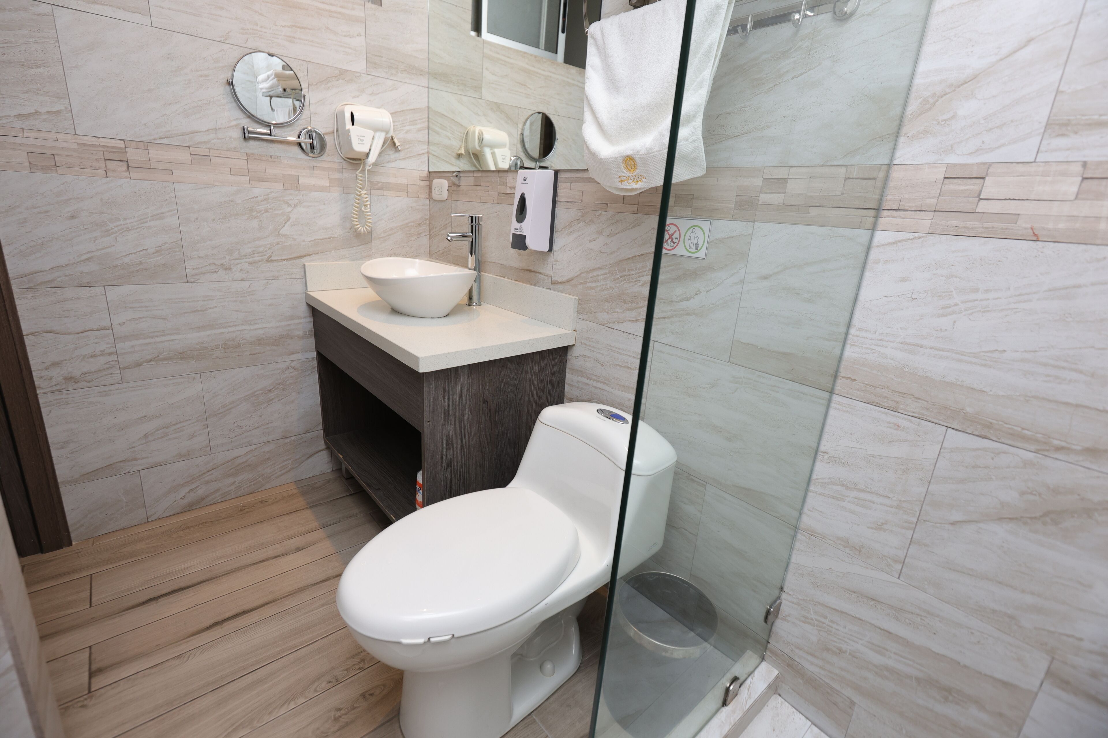 Une salle de bain moderne équipée de toilettes, d’un lavabo et d’une douche à parois en verre.
