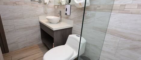 Une salle de bain moderne équipée de toilettes, d’un lavabo et d’une douche à parois en verre.