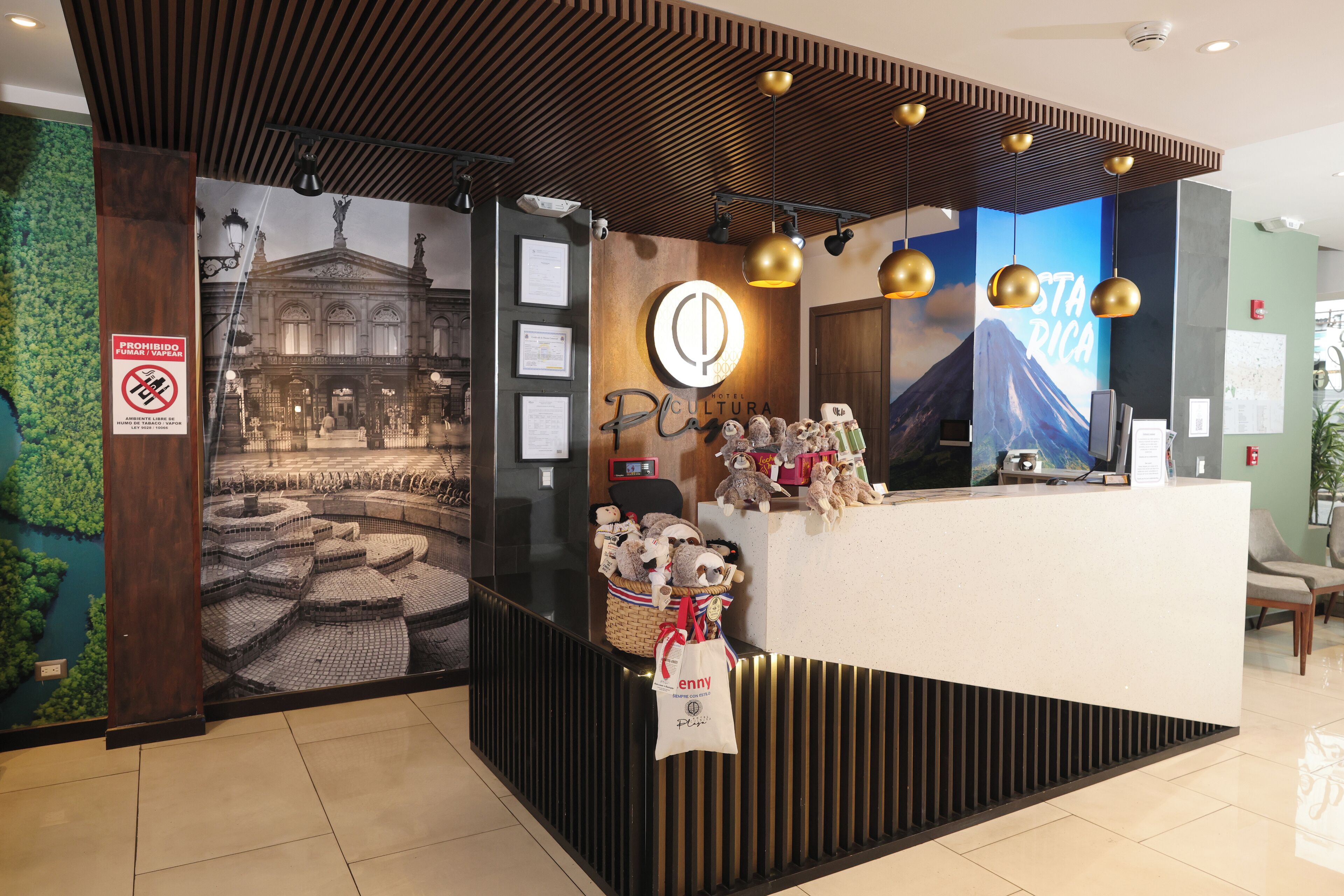 A reception desk with a wooden panel design, a wall-mounted sign prohibiting smoking, and a large poster of a building.