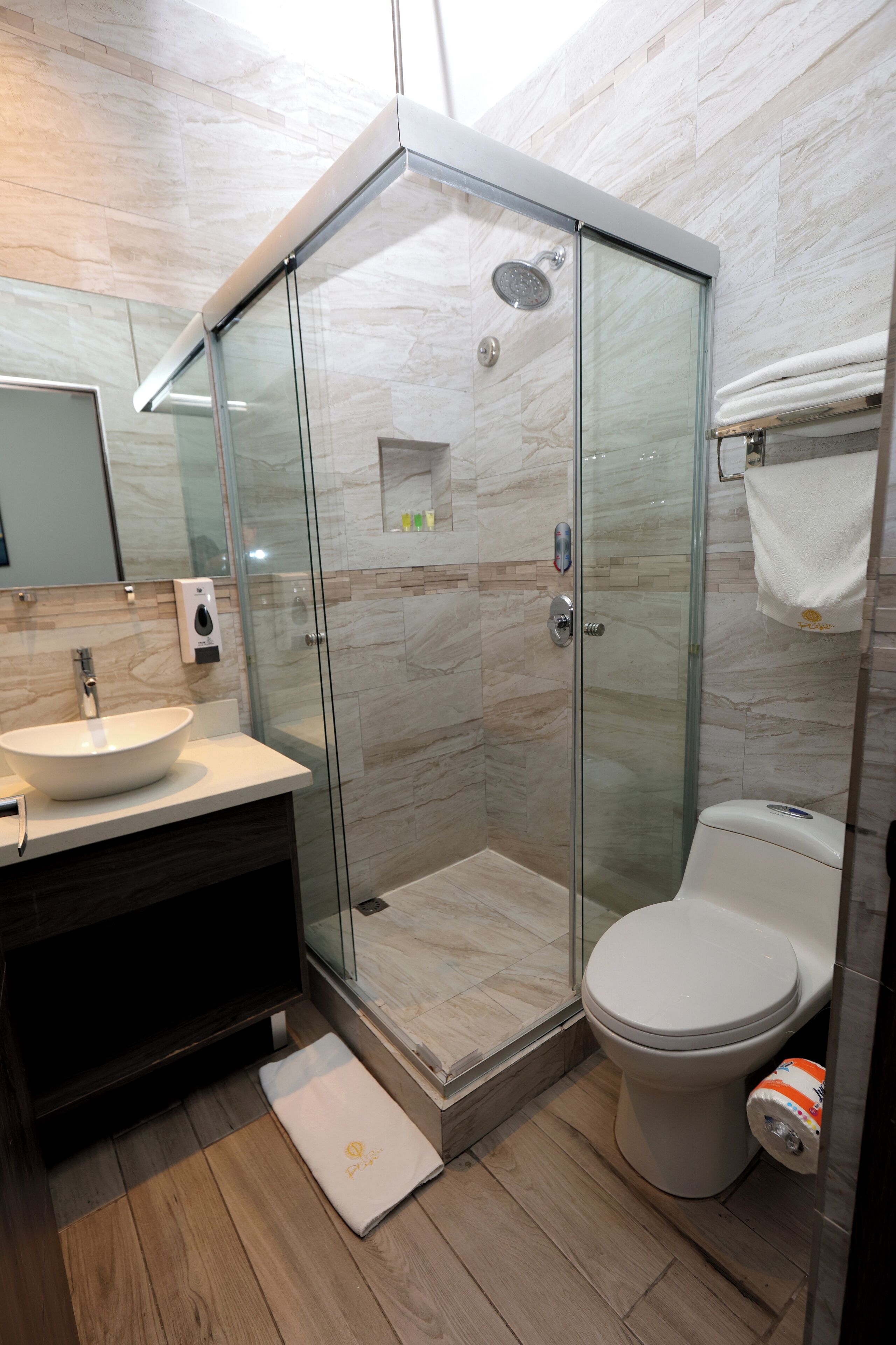 A modern bathroom with a glass-enclosed shower, a white sink, and a toilet.