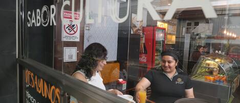 A storefront with a sign that reads 'CULTURA' and a menu board advertising 'Típico Pancakes' and 'Salads'.