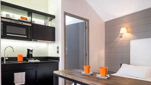 A modern kitchen with a microwave, coffee maker, and orange cups on the counter. - Beffroi - Cosy studio close to Vieux Lille - Welkeys (Lille)