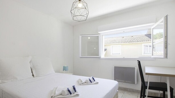 A hotel room with a bed, a desk, and a window. - Triplex Laharie - Welkeys (Bayonne)
