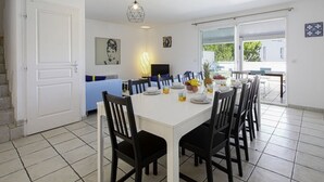 A modern kitchen with a white table set for four, black chairs, and a dining area with a view to the outside. - Triplex Laharie - Welkeys (Bayonne)