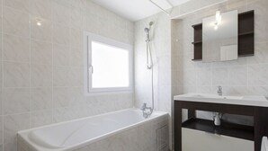 A modern bathroom with a bathtub, a shower, a sink, and a mirror. - Triplex Laharie - Welkeys (Bayonne)