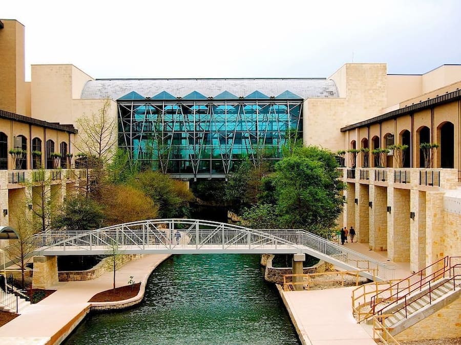 A bridge over a water channel with a modern building in the background.