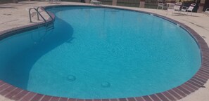 A circular swimming pool with a brick edge, a ladder, and a few lounge chairs around the perimeter. - Econo Inn Lackland AFB Seaworld (San Antonio)