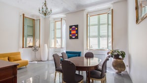 A dining area with a round table, chairs, a yellow sofa, and a potted plant. - Appartement Verrière - Welkeys (Nice)
