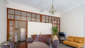 A modern living room with a large wooden dining table, comfortable seating, a television, and a sofa. - Appartement Verrière - Welkeys (Nice)