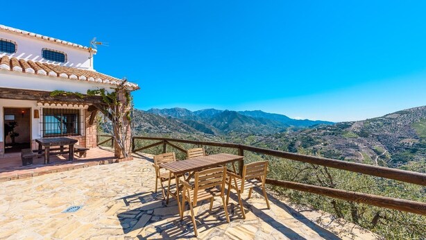 Une terrasse avec une table et des chaises, offrant une vue sur un paysage montagneux.