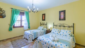 Une chambre avec deux lits, un lustre, une décoration sur le thème des navires et une fenêtre avec des rideaux.