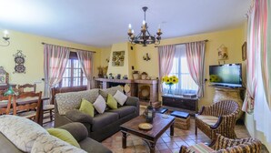 Un salon confortable avec un canapé, des fauteuils, un téléviseur et une cheminée.