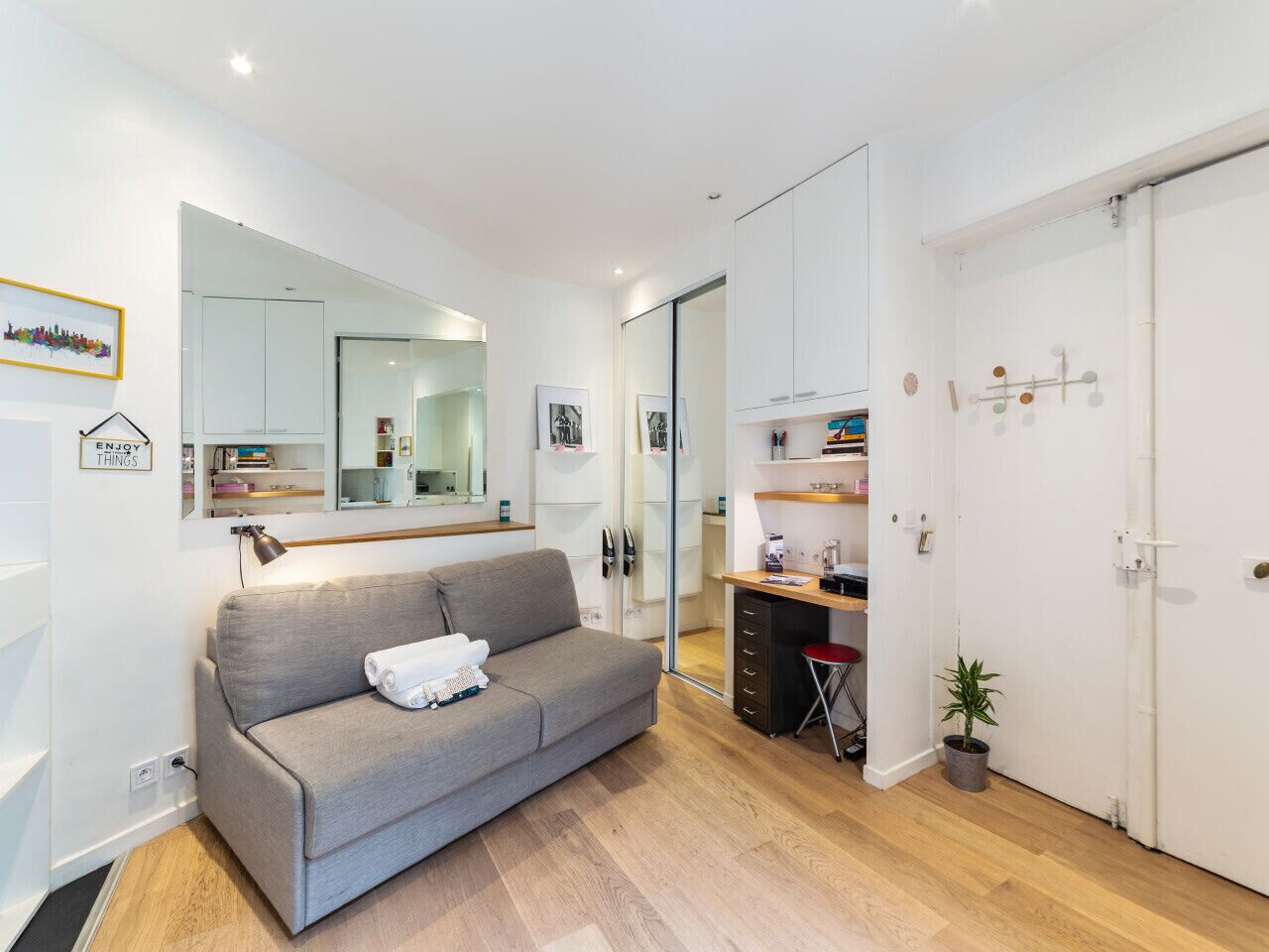 A modern living room with a grey sofa, a small table, a potted plant, and a white door.