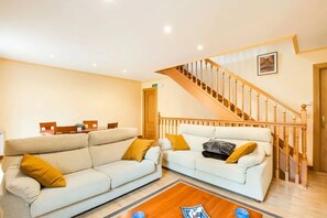 Ein Wohnzimmer mit zwei weißen Sofas, einem Holztisch und einer Treppe mit Holzgeländern.