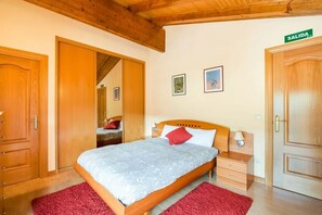 Ein Schlafzimmer mit einem Bett, einem Nachttisch, einem Holzschrank und einer Tür mit der Aufschrift 'SALIDA'.
