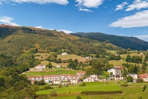 Een landelijk dorp met traditionele huizen, omringd door weelderige groene velden en heuvels.