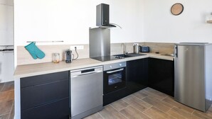A modern kitchen with a dishwasher, oven, and refrigerator. - Appartement Carnot - Welkeys (Cannes)