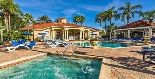 Ein Resort mit Swimmingpool, Liegestühlen und Palmen.