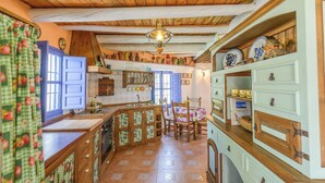 Una cocina rústica con armarios de madera, una isla central y un comedor con mesa y sillas.