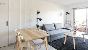 Ein modernes Wohnzimmer mit einem Holzespeisetisch, einer grauen Couch und einem kleinen Couchtisch.