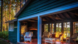 Eine Holzhütte mit Veranda, Korbstühlen und Kamin.