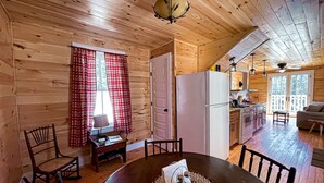 Un interior acogedor de cabaña con comedor, cocina y un balcón.