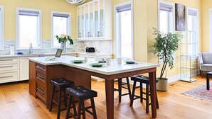 Una cocina moderna con una isla central, taburetes de bar y una planta en maceta.