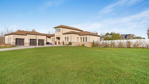 A two-story house with a large front lawn, garage, and a well-maintained garden.