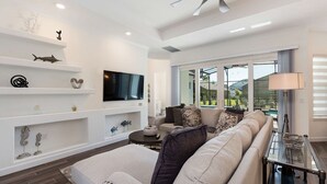 A modern living room with a sofa, TV, and decorative items on shelves. - Your Ultimate Luxury Getaway in the Providence Golf Community (Davenport)