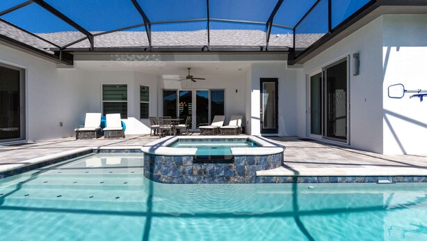 A swimming pool with a sunken hot tub, surrounded by lounge chairs and a table. - Your Ultimate Luxury Getaway in the Providence Golf Community (Davenport)