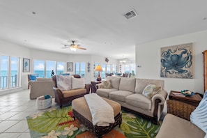 Relax in this spacious living room with a high ceiling, ceiling fan, and stunning view.