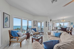 Enjoy a panoramic ocean view from the large window in this stylish living area, featuring comfortable seating and a coffee table.