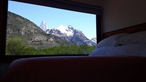 Ein Bett mit Blick auf die Berge durch ein Fenster.