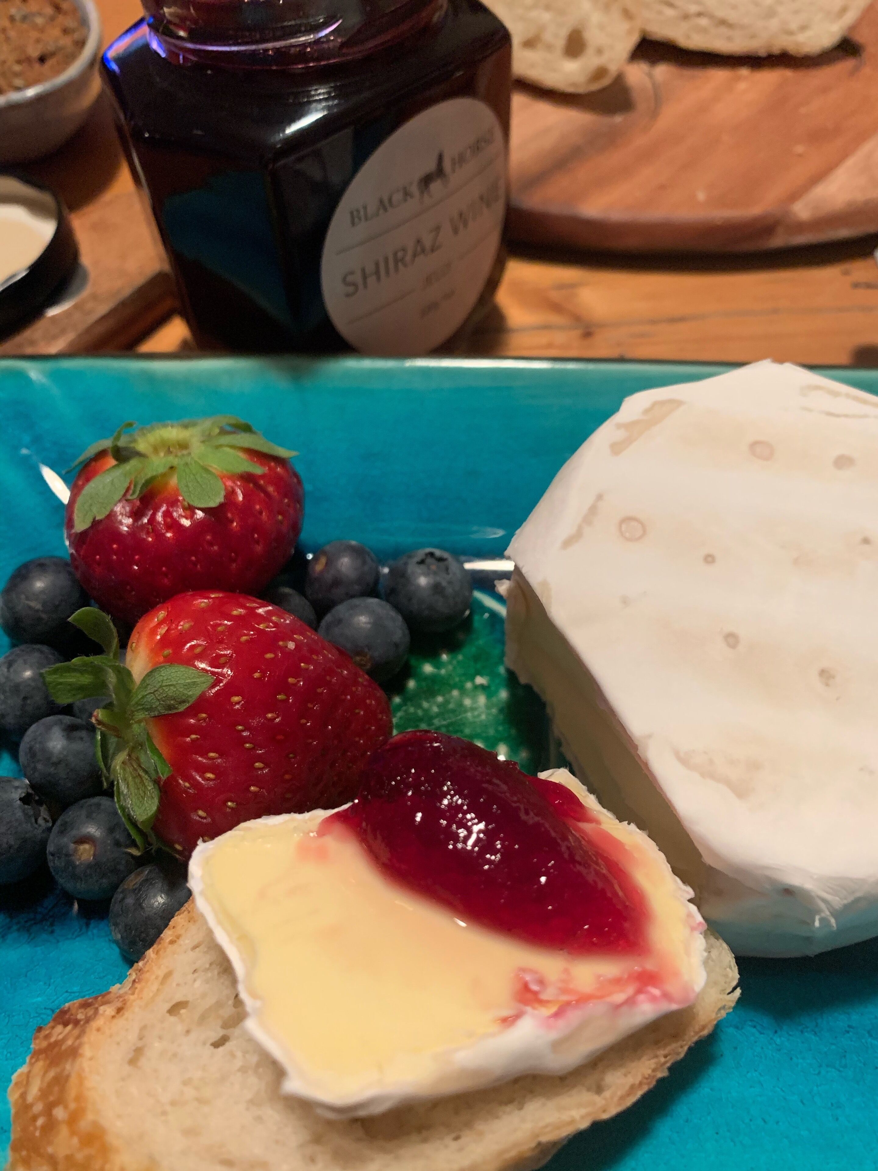 A plate with a piece of cheese, strawberries, and blueberries.