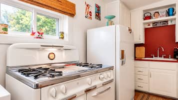 A kitchen with a stove, refrigerator, and various kitchen items.